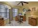 Bright home office features a wooden desk, neutral chair, large windows, and a ceiling fan at 5974 San Michelle Dr, Sarasota, FL 34243
