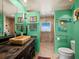 Unique bathroom with green walls, wooden vanity, stone sink, and tiled walk-in shower, blending natural elements and modern design at 691 Linley St, Longboat Key, FL 34228