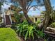 A view of the house with a deck and stairs beyond lush, professionally landscaped foliage and trees at 691 Linley St, Longboat Key, FL 34228