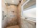 Shower with brown tiled walls, built-in niche, safety bar, rainfall shower head, and frosted glass window, providing a spa-like experience at 691 Linley St, Longboat Key, FL 34228