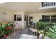 Charming front porch with bistro table, chair, lush plants, and access to the front door at 7860 Palm Aire Ln # 104, Sarasota, FL 34243