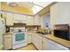 Efficient kitchen features white appliances, tile flooring, and bright lighting for a practical cooking space at 7860 Palm Aire Ln # 104, Sarasota, FL 34243