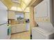 Efficient kitchen with stacked laundry machines; features white appliances, tile flooring, and bright lighting at 7860 Palm Aire Ln # 104, Sarasota, FL 34243