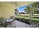 Relaxing screened patio with ceiling fan and tile floor overlooks a lush green space at 7860 Palm Aire Ln # 104, Sarasota, FL 34243
