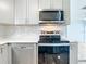 Stainless steel dishwasher and oven with gray cabinets, mosaic backsplash, and white counters at 8430 Truman St, Englewood, FL 34224