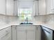 Close-up of kitchen sink and faucet, gray cabinets, mosaic backsplash and white countertop at 8430 Truman St, Englewood, FL 34224