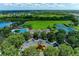 Aerial view of community clubhouse and pool area with tennis courts and green space near a scenic lake at 9828 58Th E St, Parrish, FL 34219