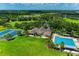Aerial view showcases the clubhouse, pool, and tennis courts, surrounded by lush landscaping and green spaces at 9828 58Th E St, Parrish, FL 34219