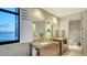 A well-lit bathroom with double sinks, modern fixtures, and a stunning ocean view through shuttered windows at 1241 Gulf Of Mexico Dr # 1005, Longboat Key, FL 34228