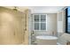 Bright, spacious bathroom boasts a glass shower and standalone tub with natural light from shuttered windows at 1241 Gulf Of Mexico Dr # 1005, Longboat Key, FL 34228