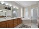 Bright bathroom featuring a large tub, glass-enclosed shower, and double sink vanity at 14205 Nighthawk Ter, Lakewood Ranch, FL 34202