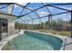 A backyard pool is surrounded by a screened-in enclosure with a safety fence, backing up to mature trees at 14205 Nighthawk Ter, Lakewood Ranch, FL 34202