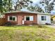 Charming, single-story brick home featuring a vibrant pink door, well-maintained lawn, and mature shade trees at 1520 2Nd E Ave, Bradenton, FL 34208