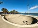 Outdoor skate park with a smooth concrete surface, set against a scenic waterfront with palm trees and bridge views at 1520 2Nd E Ave, Bradenton, FL 34208