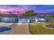 Charming single-story home boasting a paver driveway, separate garage, and freshly landscaped yard at dusk at 1950 Fairview Dr, Englewood, FL 34223