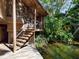 Wooden stairway leading to a charming house surrounded by lush greenery and calm waters at 2613 Temple St, Sarasota, FL 34239