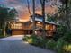 Charming multi-level home with natural wood siding, a serene pond, and manicured landscaping at twilight at 2613 Temple St, Sarasota, FL 34239