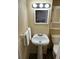 Cozy bathroom with a pedestal sink, framed mirror, vanity lighting, and toilet at 3308 W Dewey St, Tampa, FL 33607