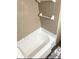 Clean white bathtub with neutral tone ceramic tile surround and updated towel racks at 3308 W Dewey St, Tampa, FL 33607
