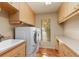 Laundry room with front-loading washer and dryer, storage cabinets and terracotta tile flooring at 3970 Country View Dr, Sarasota, FL 34233