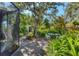 Landscaped backyard has patio and pathway through lush plantings, a large shade tree, and a small building at 4062 S Shade Ave, Sarasota, FL 34231