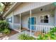 Charming front porch featuring decorative railings, white columns, and a vibrant blue door, creating a welcoming entrance at 4062 S Shade Ave, Sarasota, FL 34231