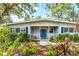 Inviting home with a welcoming front porch framed by lush tropical landscaping and a bright blue front door at 4062 S Shade Ave, Sarasota, FL 34231