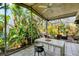 Screened-in patio with tiled flooring and an outdoor dining area surrounded by lush tropical foliage at 4062 S Shade Ave, Sarasota, FL 34231