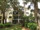 Three-story condo building featuring private screened-in patios surrounded by lush landscaping and mature trees at 425 30Th W Ave # C210, Bradenton, FL 34205