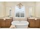 Beautiful bathroom featuring dual vanities, a soaking tub, and a window with plantation shutters at 4670 Antrim Dr, Sarasota, FL 34240