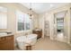 Bright bathroom features a luxurious soaking tub, plantation shutters, and stylish vanity with modern lighting at 4670 Antrim Dr, Sarasota, FL 34240
