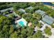 Aerial view of tennis courts and a pool surrounded by mature trees in a vibrant community at 5187 Lake Village Dr # 4, Sarasota, FL 34235
