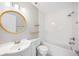 Well-lit bathroom features round mirror, modern fixtures, shower-tub combination, and stylish decorative shelving at 5187 Lake Village Dr # 4, Sarasota, FL 34235
