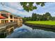 Clubhouse with a dock overlooking a pond with landscaping and a lush green golf course at 5187 Lake Village Dr # 4, Sarasota, FL 34235