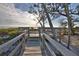 Wood boardwalk and deck leading to a serene beach with lush greenery at 5611 Gulf Of Mexico Dr # 5, Longboat Key, FL 34228