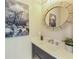 Modern powder room featuring stylish vanity, round mirror, decorative art, and neutral wallpaper at 870 N Shore Dr, Anna Maria, FL 34216