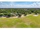 Wide aerial perspective displays park with green spaces, walking paths, playground, trees and distant houses beneath a bright sky at 13324 Purple Finch Cir, Lakewood Ranch, FL 34202