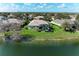 Aerial perspective of a house on the lake featuring a screened pool, well-kept lawn and mature trees at 13324 Purple Finch Cir, Lakewood Ranch, FL 34202