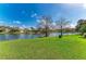 Scenic lake view featuring a well-maintained lawn, mature trees, and charming houses in the background at 13324 Purple Finch Cir, Lakewood Ranch, FL 34202