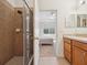 Bathroom with walk-in shower, tan tile, and view through doorway to the bedroom at 2345 Felicity Pl, North Port, FL 34289