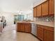 Bright kitchen featuring wooden cabinets, stainless steel dishwasher, mosaic backsplash and tile flooring at 2345 Felicity Pl, North Port, FL 34289