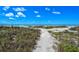 Sandy path leading to the beach with dunes and a bright blue sky at 4234 Gulf Of Mexico Dr # E2, Longboat Key, FL 34228