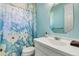 A bright bathroom with a vanity, toilet, and shower with a floral shower curtain at 5750 Saddle Oak Trl, Sarasota, FL 34241
