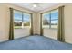 Bedroom with plush blue carpeting, ceiling fan, and two large windows at 5750 Saddle Oak Trl, Sarasota, FL 34241