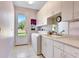 Well-organized laundry room with white cabinetry, sink, and a door leading to the outdoors at 5750 Saddle Oak Trl, Sarasota, FL 34241