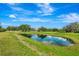 Scenic pond view with lush green grass surrounding the beautiful home at 5750 Saddle Oak Trl, Sarasota, FL 34241