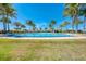 Expansive community pool surrounded by palm trees, sun umbrellas and tropical landscaping offers a resort-style living experience at 701 Maraviya Blvd, Nokomis, FL 34275