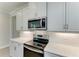 Modern kitchen featuring stainless steel appliances, white cabinets, and quartz countertops for a sleek and stylish look at 701 Maraviya Blvd, Nokomis, FL 34275