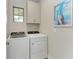 Laundry room with modern washer and dryer units, storage cabinets, and natural light at 701 Maraviya Blvd, Nokomis, FL 34275