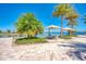 Inviting lakeside patio with dining set shaded by umbrellas, surrounded by lush tropical landscaping, for relaxed outdoor living at 701 Maraviya Blvd, Nokomis, FL 34275